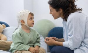Bambino con cuffia EEG ascolta attentamente un genitore che gli parla.
