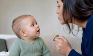 Neonato di sei mesi osserva il genitore parlare mentre il ciuccio è tolto.