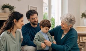 Una nonna accudisce il nipotino mentre i genitori osservano sereni nella casa condivisa.